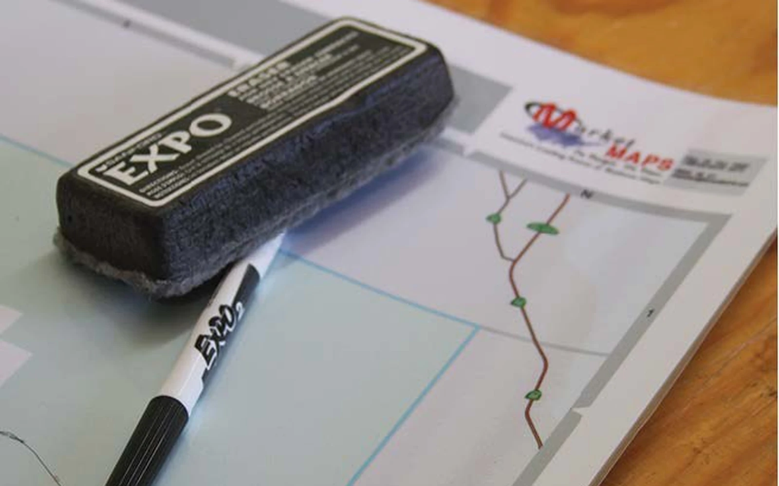 An eraser and marker resting on the curled edge of a glossy laminated map