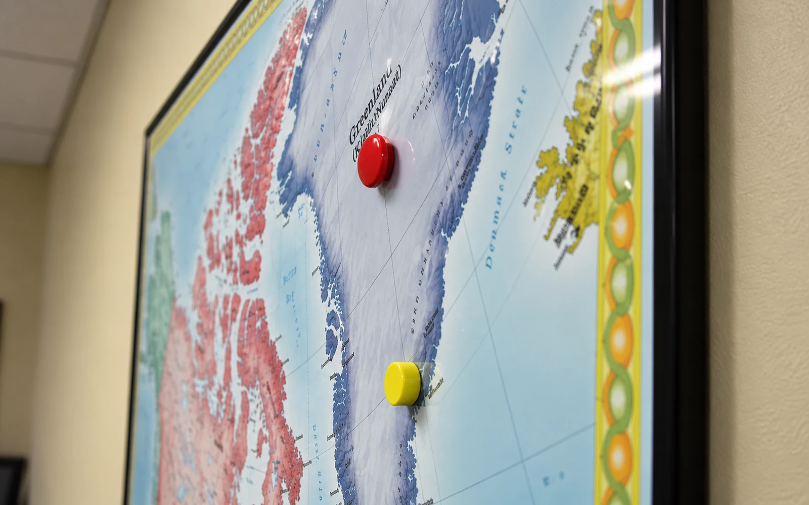 Red and yellow magnets marking locations on a framed wall map