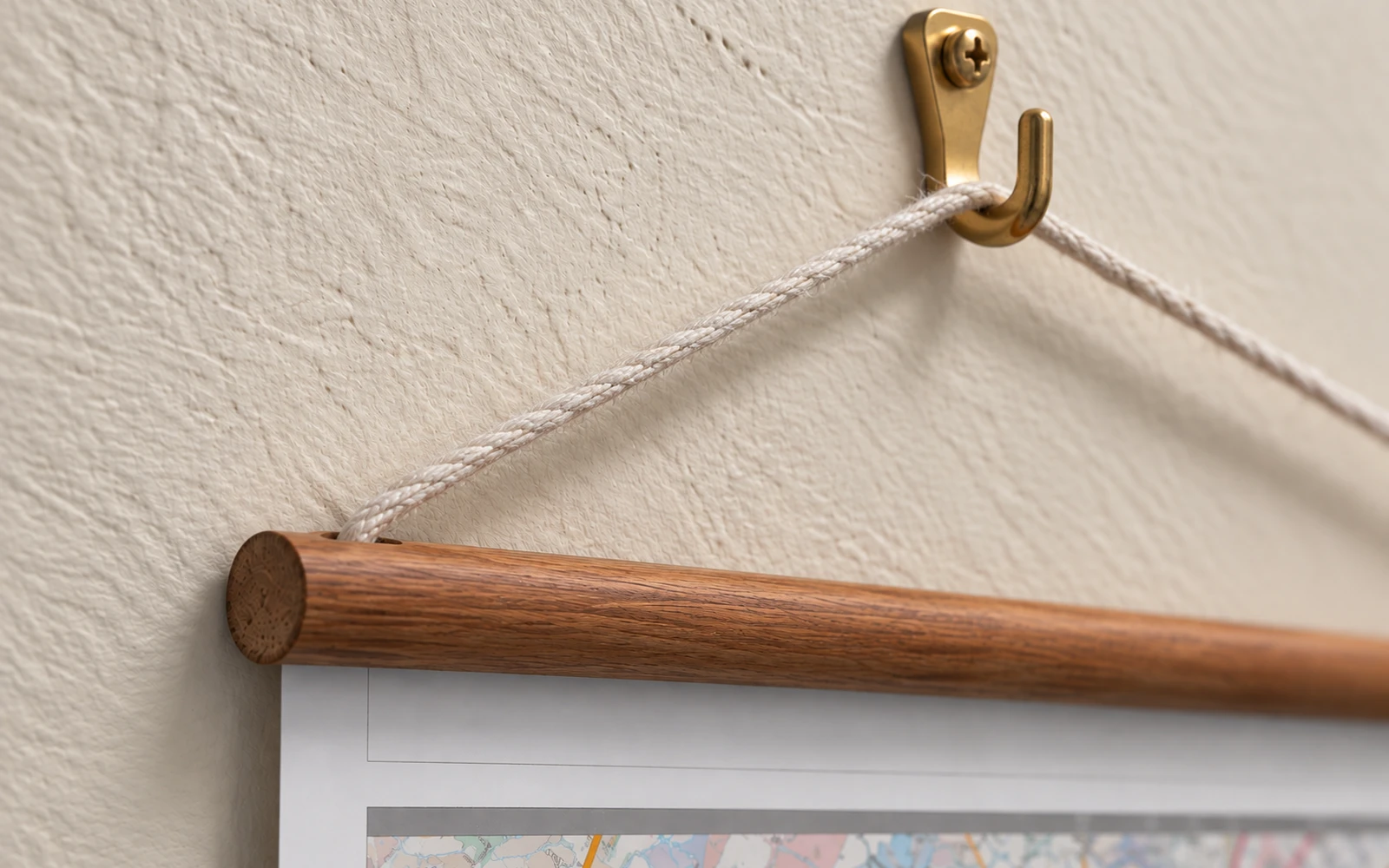 The cord of a railed map looped over a brass wall hook