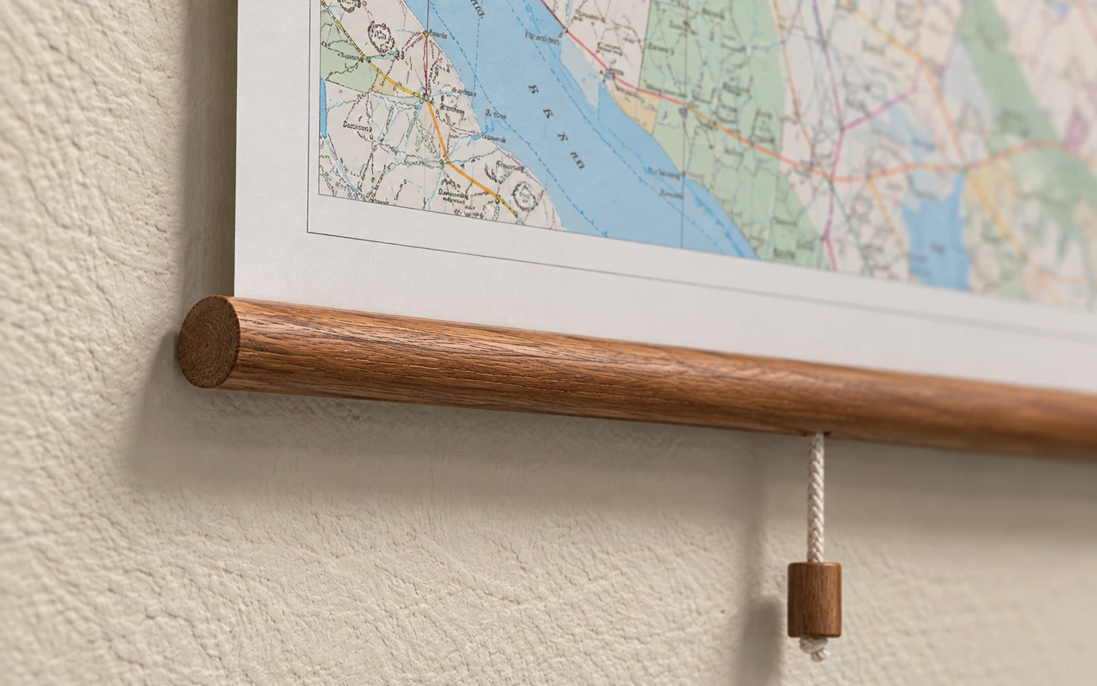 The lower rail of a mounted map with its weighted cord finial