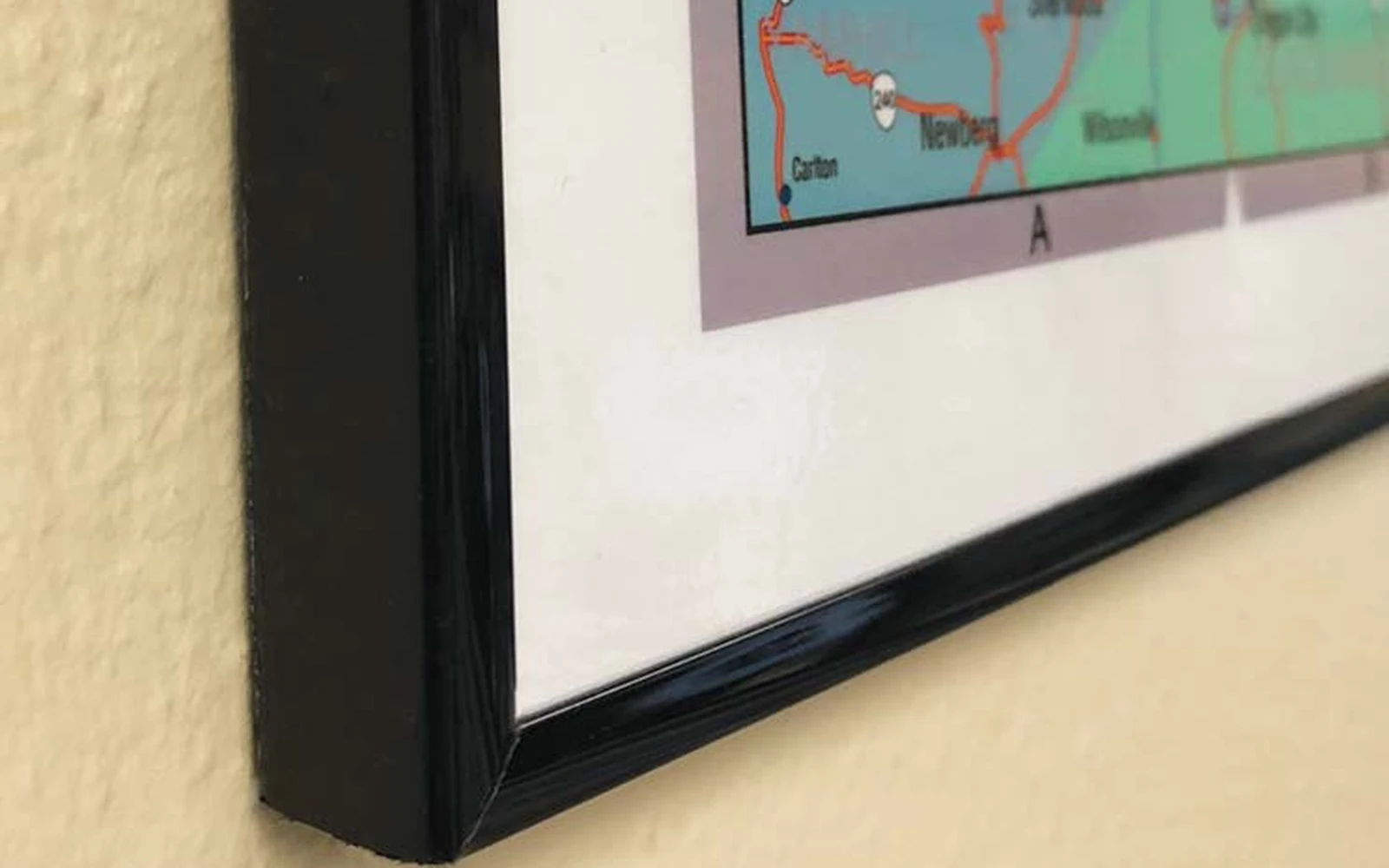 The corner of a mounted wall map finished in a slim black frame