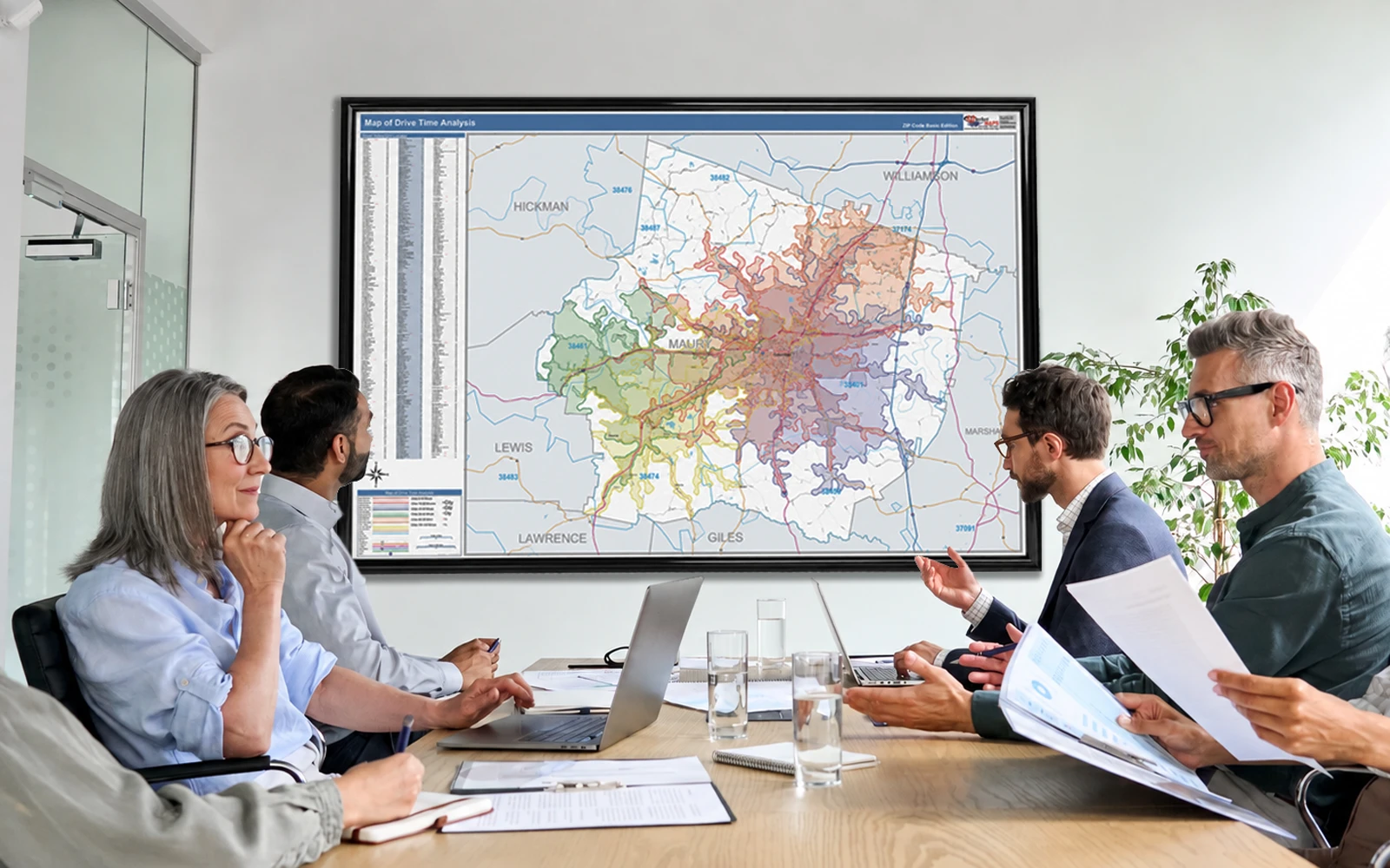 Colleagues in a boardroom meeting beside a framed wall map