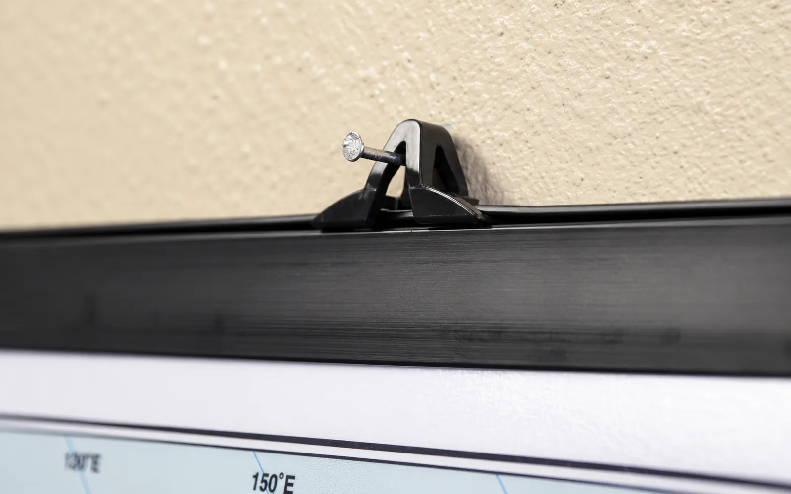 A black plastic rail gripping the edge of a map, with its hanging clip