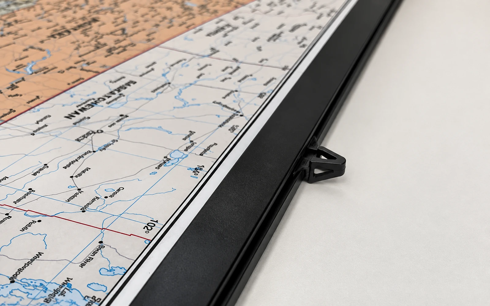 A black plastic rail running along the lower edge of a laminated wall map