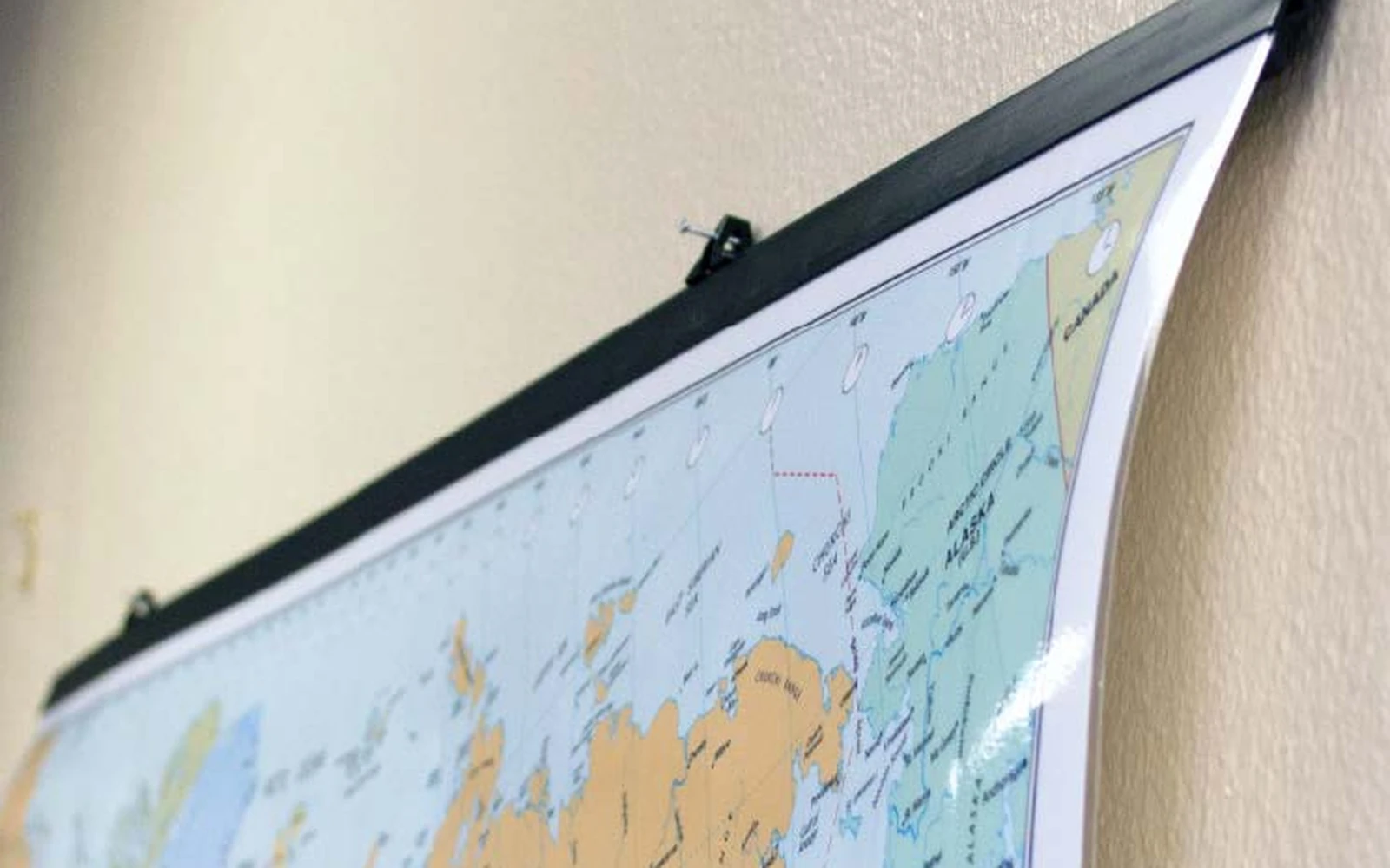 A railed wall map seen from an angle, hanging flat against the wall