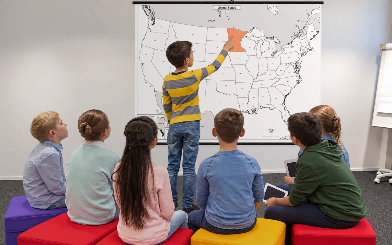 Children in a classroom looking up at a railed wall map