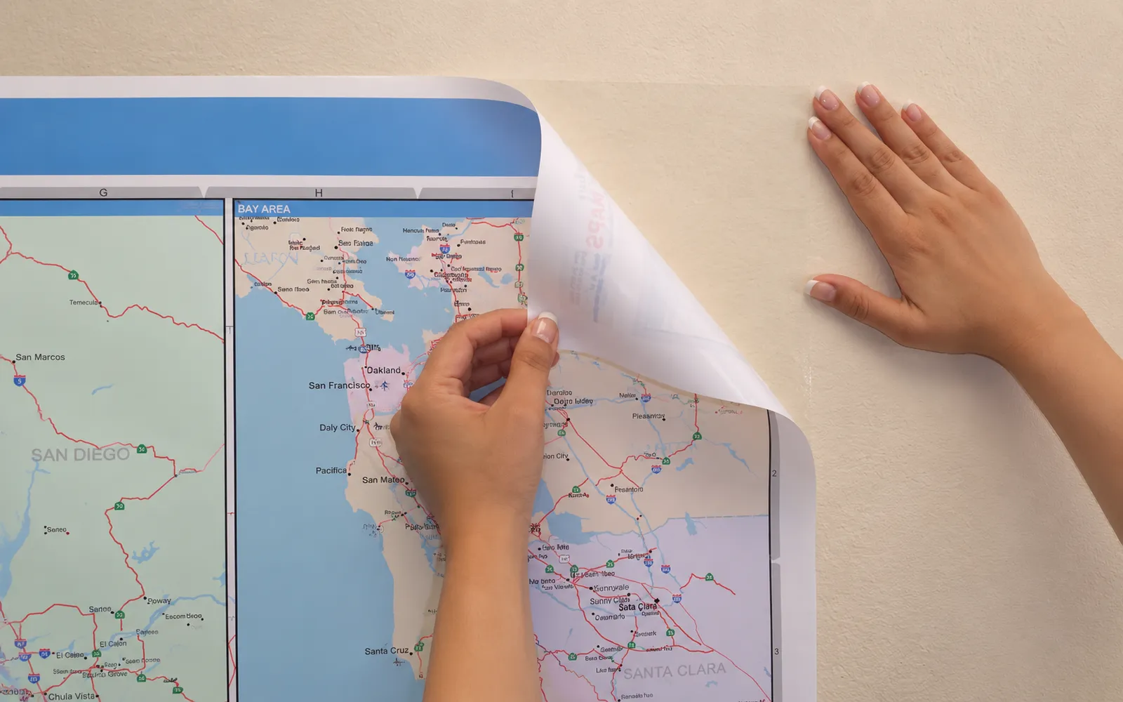 A restickable map sheet being peeled back from a painted wall