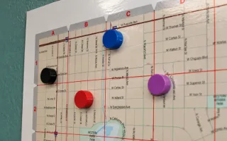 Round coloured magnets placed across the face of a wall-mounted map