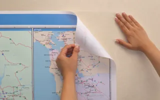 A restickable map sheet being peeled back from a painted wall